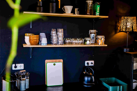 Kitchen area at Pean Buiten - Natuurhuisjes Friesland with shelves, glasses, bowls, and an electric kettle.