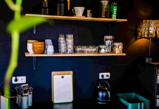 Zona de cocina en Pean Buiten - Natuurhuisjes Friesland con estantes, vasos, tazones y hervidor eléctrico.