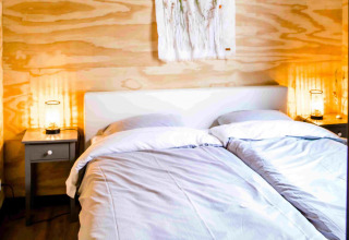 Cozy glamping accommodation at Pean Buiten - Natuurhuisjes Friesland, featuring twin beds and warm lighting.