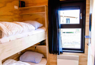 Glamping accommodation at Pean Buiten - Natuurhuisjes Friesland with bunk beds and bright window.