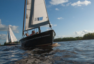 Veleros navegando en un lago en Pean Buiten - Natuurhuisjes Friesland, ideal para glamping o camping natural.