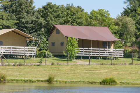 Glamping-indkvartering i safaritelte på Camping Village de la Guyonnière, Vendée ved en sø og grønne omgivelser.
