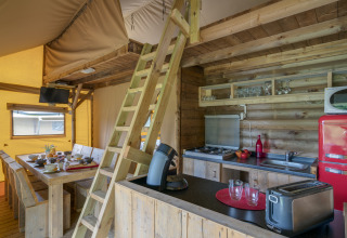 Interno di una tenda safari glamping al Camping Village de la Guyonnière, con cucina e zona pranzo.