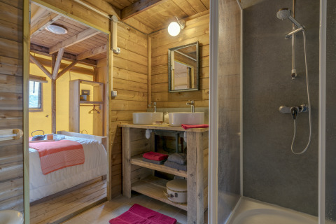 Bathroom and bedroom with wooden walls in glamping at Camping Village de la Guyonnière – Safaritenten Vendée.
