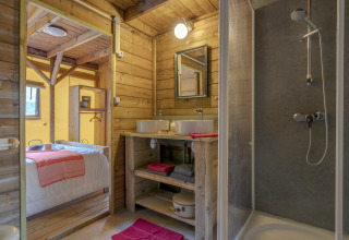 Salle de bain et chambre en bois dans la tente safari glamping du Camping Village de la Guyonnière, Vendée.