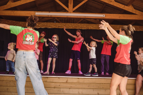 Kinderen en volwassenen dansen samen op het podium bij de Lenny Club op Camping Village de la Guyonnière, Vendée.