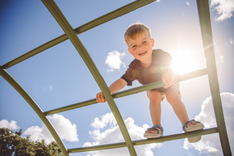 Bambino che gioca su una struttura da arrampicata al sole a Camping Village de la Guyonnière – Safaritenten Vendée.