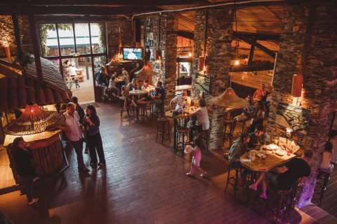 Gezinnen genieten van eten en drinken in het rustieke restaurant van Camping Village de la Guyonnière – Safaritenten Vendée.
