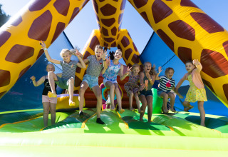 Des enfants jouent sur un château gonflable girafe au Camping Village de la Guyonnière dans la Vendée.