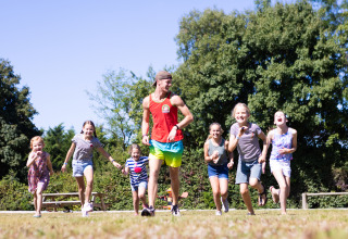 En gruppe børn og en voksen leger og løber sammen på Camping Village de la Guyonnière – Safaritenten Vendée.