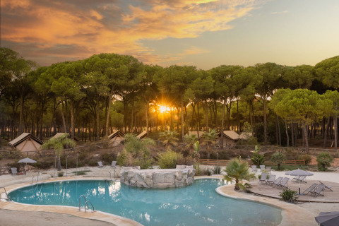 Glamping at Huttopia Parque de Doñana, Andalusia with pool, tents and forest at sunset.
