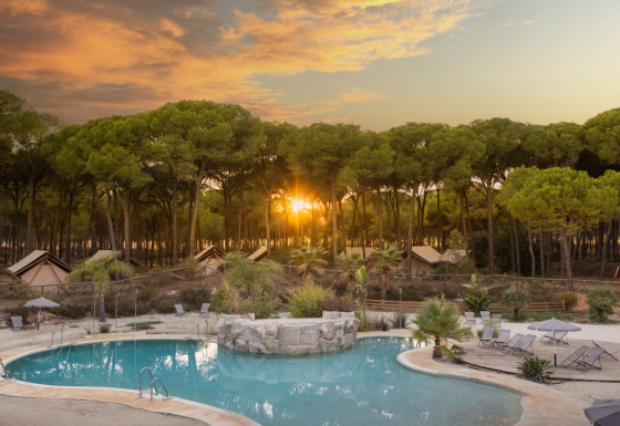 Glamping au Huttopia Parque de Doñana, Andalousie, avec piscine, tentes et forêt au coucher du soleil.