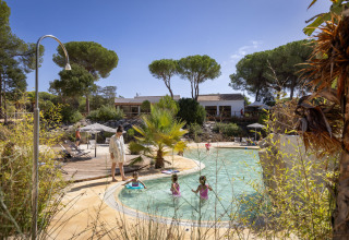Gezin geniet bij het zwembad, omringd door natuur, in Huttopia Parque de Doñana glamping in Andalusië.