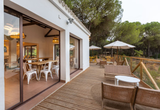 Terrasse en bois avec salon extérieur à Huttopia Parque de Doñana – Glamping Andalousie, entourée de pins.