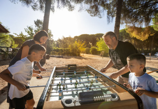 Familie genießt eine Runde Tischfußball im Freien bei Huttopia Parque de Doñana Glamping in Andalusien.