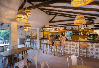 Gemütliche Bar im Innenbereich von Huttopia Parque de Doñana – Glamping Andalusië mit rustikalem Dekor.