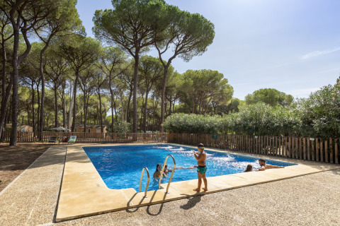 Children enjoy swimming in the pool at Huttopia Parque de Doñana – Glamping Andalusië, surrounded by pine trees.