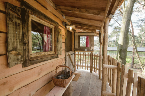 Treehouse glamping accommodation at Recreatiepark d'n Mastendol in Brabant, Netherlands, rustic porch view.