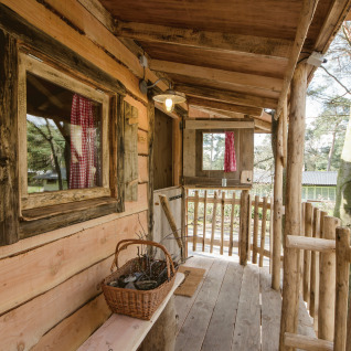 Alojamiento glamping en casa del árbol en Recreatiepark d'n Mastendol, Brabant, Países Bajos, con porche rústico.