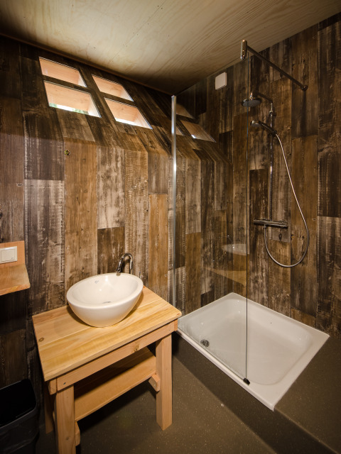 Baño moderno con paredes de madera, ducha y lavabo en una cabaña glamping en Recreatiepark d'n Mastendol, Boomhut Brabant.