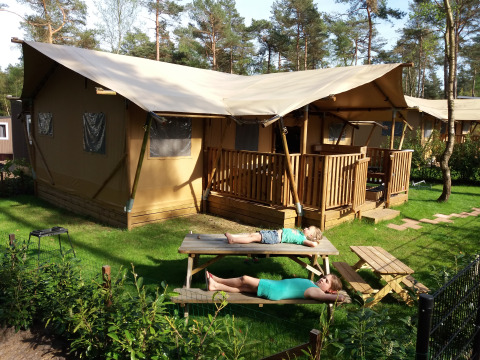 Deux personnes se détendent sur une table devant une safarilodge à Ons plekje in het bos, en Gueldre.