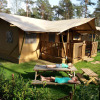 Two people relaxing on a picnic table in front of a safari lodge at Ons plekje in het bos, Gelderland.