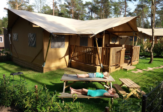 Twee personen relaxen op een picknicktafel bij een safarilodge van Ons plekje in het bos in Gelderland.