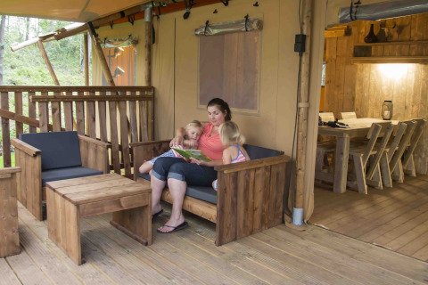 Gezin geniet samen van een boek bij een safarilodge in Ons plekje in het bos, Gelderland.
