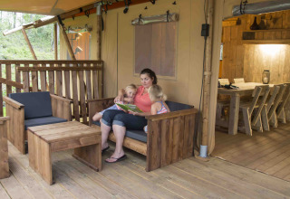 En familie slapper af på terrassen i en safarilodge ved Ons plekje in het bos, Gelderland, Holland.