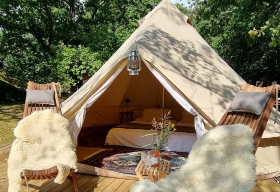 Alloggio glamping al Sävö Bed and Breakfast con tenda di lusso, sedie in legno e terrazza accogliente.