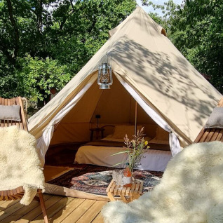 Glampingverblijf bij Sävö Bed and Breakfast met luxe tent, houten stoelen en gezellige buitenruimte in het groen.