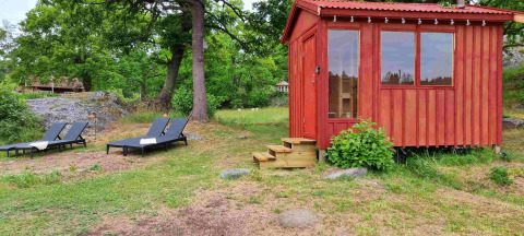 Cabane rouge en bois et deux transats dans la nature à Sävö Bed and Breakfast - Glampingtenten Södermanland.