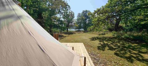Glamping-Zelt bei Sävö Bed and Breakfast in Södermanland mit Blick auf Wiese und Wald nahe See.