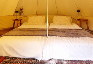 Glamping-Unterkunft mit zwei Betten, dekorativen Kissen und Teppich im Sävö Bed and Breakfast, Södermanland.