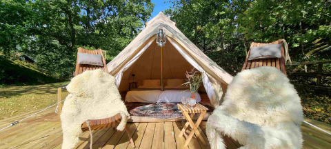 Luxury glamping tent with cozy decor, sheepskin chairs, and nature views at Sävö Bed and Breakfast.