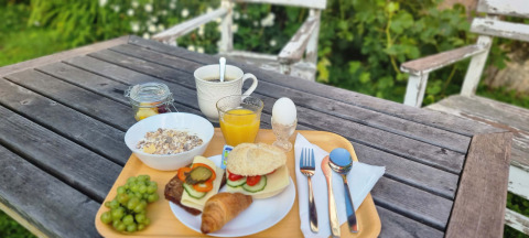 Colazione gustosa all'aperto su tavolo in legno con pane, croissant, frutta, succo e caffè al glamping.