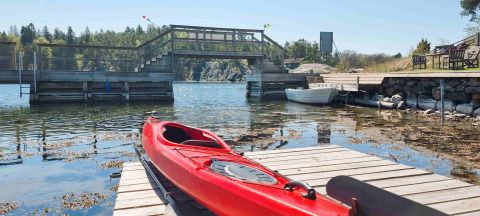 Kayak rouge sur un ponton à Sävö Bed and Breakfast - Glampingtenten Södermanland avec vue lac paisible.