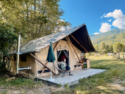 Hébergement glamping à Huttopia Vallouise, Hautes-Alpes, avec tente, terrasse en bois et vue sur les montagnes.