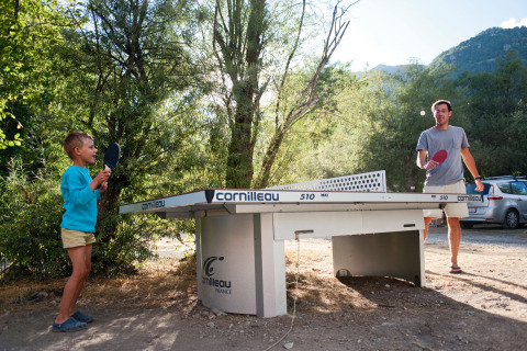 Un adulto e un bambino giocano a ping pong all'aperto a Huttopia Vallouise - Glamping Hautes-Alpes.
