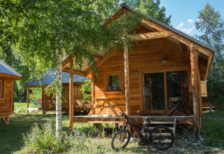 Sistemazione glamping presso Huttopia Vallouise nelle Hautes-Alpes con chalet in legno, bici e natura.