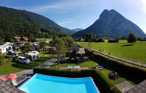 Camping Lazy Rancho en Suiza con iglús de madera, piscina, y vistas panorámicas a las montañas.