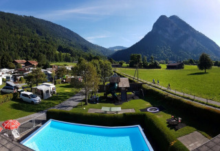 Camping Lazy Rancho met houten iglo’s, zwembad en uitzicht op de bergen in Zwitserland.