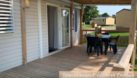 Terraza cubierta de Luxe Camping Borken am See, alojamiento de glamping con mesa, sillas y vistas al jardín.