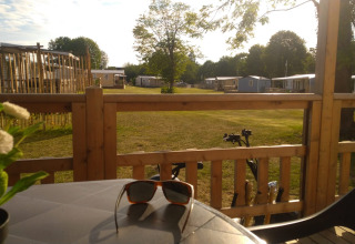 Vista da una terrazza con occhiali da sole sul tavolo al Luxe Camping Borken am See - Glamping NRW.