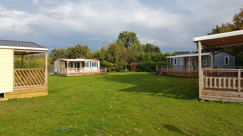 Groene grasveld met luxe houten glampingtenten en veranda’s bij Luxe Camping Borken am See in Duitsland.