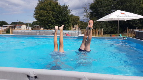 Due bambini fanno la verticale in piscina al Luxe Camping Borken am See - Glamping Noordrijn-Westfalen, immersi nella natura.