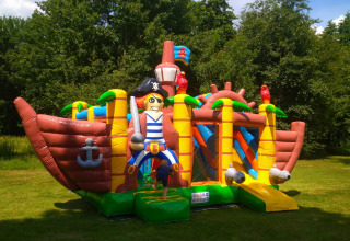 Barco pirata hinchable en césped para niños, Luxe Camping Borken am See, Glamping Noordrijn-Westfalen.