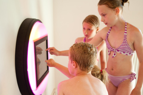 Kinder spielen in Badebekleidung an einem interaktiven Bildschirm bei Luxe Camping Borken am See - Glamping Nordrhein-Westfalen.