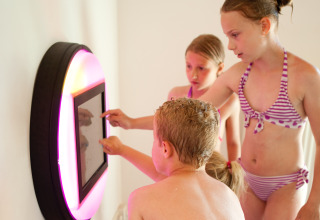 Kinderen in zwemkleding ontdekken een interactief scherm bij Luxe Camping Borken am See - Glamping Noordrijn-Westfalen.