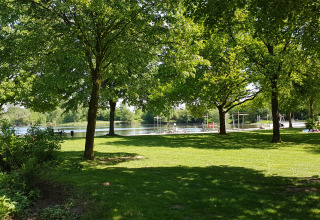 Area campeggio verde con alberi e lago presso Luxe Camping Borken am See - Glamping Noordrijn-Westfalen.